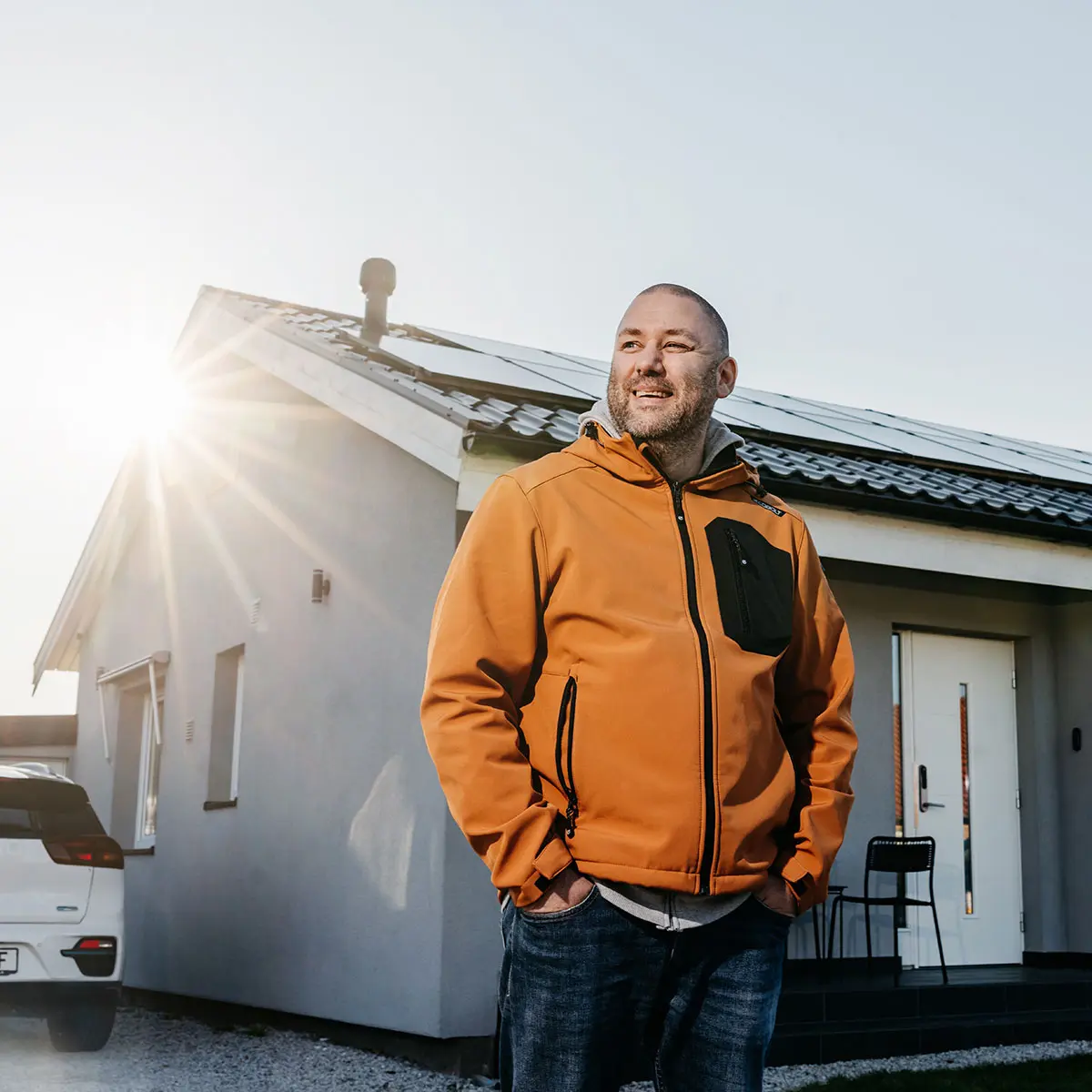 En husägare som står framför sitt hus med solpaneler
